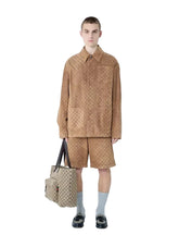 Person wearing a beige outfit with a matching bag on a white background