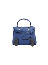 A blue leather handbag with a top handle, silver-tone hardware, and dark gray rubber feet attached to the bottom, photographed against a neutral light gray background.
