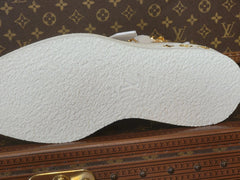 A close-up of a white textured shoe sole with an embossed Louis Vuitton monogram, resting on a brown Louis Vuitton monogram surface.
