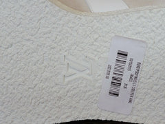 Close-up of a white textured fabric surface with an embossed LV logo and a white product tag with barcode and text.