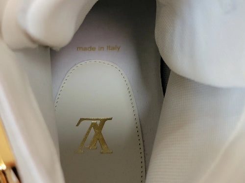 Close-up of the interior of a white Louis Vuitton shoe, showing the white leather insole with a gold LV logo and 'made in Italy' text.