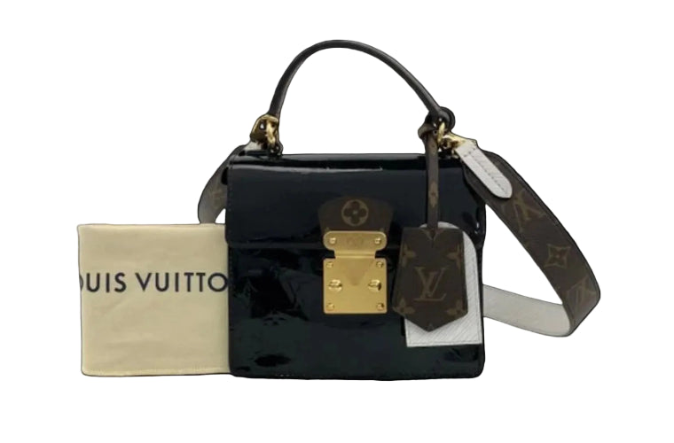 Louis Vuitton handbag with gold lock and tags on a black background