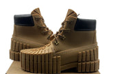 Tan boots with black soles on a cardboard box against a white background
