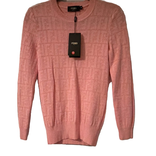 Pink sweater with a Fendi tag on a white door
