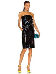 Woman wearing a strapless, reflective black dress with colorful highlights on a white background.