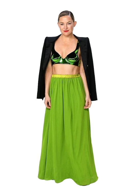 Woman wearing a green crop top and long skirt with a black jacket on a white background