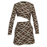 A long-sleeve mini dress with a brown and off-white chain-link pattern, featuring a crossover front and a curved side cutout, shown against a plain white background.