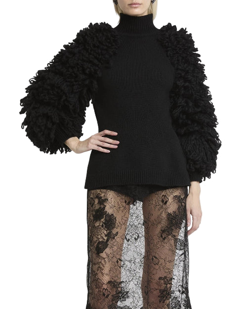 Black sweater with textured sleeves worn by a person on a white background