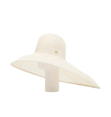 An off-white wide-brimmed sun hat with a small gold interlocking CC logo on the front, displayed on a matching cream-colored mannequin stand against a white background.