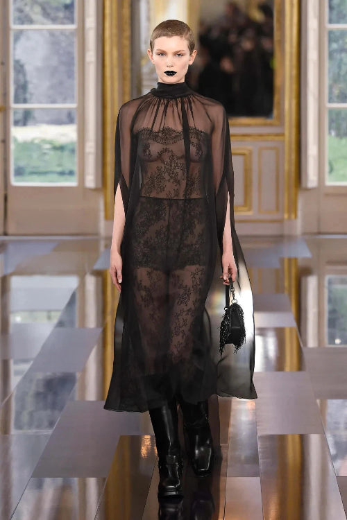 Model wearing a black lace dress in an elegant interior setting