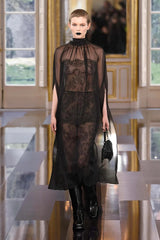Model wearing a black lace dress in an elegant interior setting