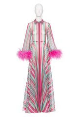 A long-sleeved maxi dress with vertical pink, mint green, and white stripes, featuring bright pink feather trim at the cuffs and a matching striped bow at the collar, displayed on a white mannequin.