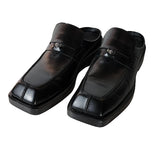 Pair of black leather shoes on a light wooden floor.