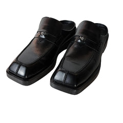 Pair of black leather shoes on a light wooden floor.