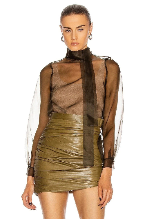 Woman wearing a sheer top and green leather skirt on a white background