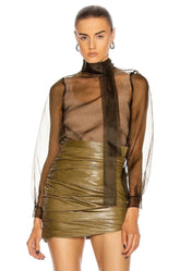 Woman wearing a sheer top and green leather skirt on a white background