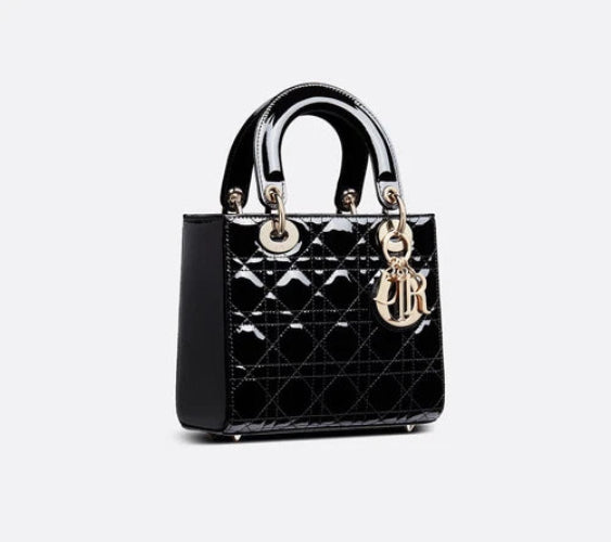 Black quilted handbag with gold hardware on a light gray background