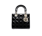 Black quilted handbag with gold hardware on a light gray background
