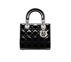 Black quilted handbag with gold hardware on a light gray background