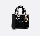 Black quilted handbag with gold hardware on a light gray background