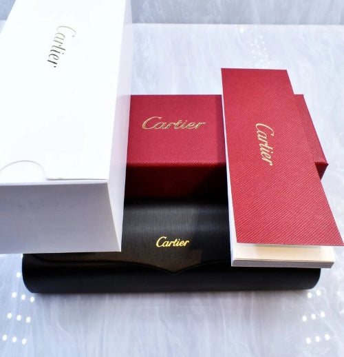 Cartier packaging including a red box, black clutch bag, and white envelope on a light gray background.