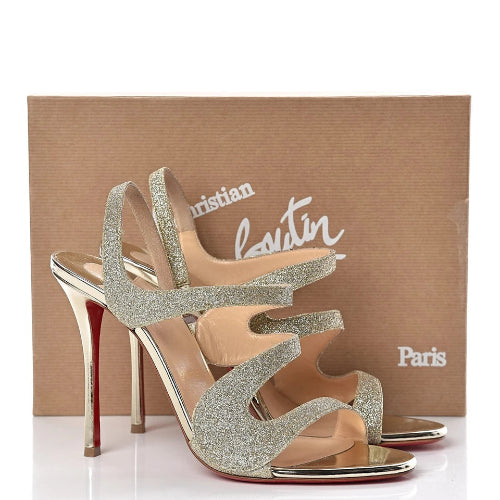 Sparkly high-heeled shoes in front of a Christian Louboutin box.
