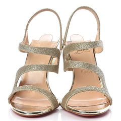 Pair of gold glittery high-heeled sandals on a white background