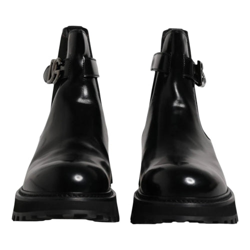 Pair of black leather boots with buckle details on a white background