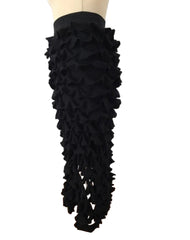 Black ruffled skirt on a mannequin against a white wall.