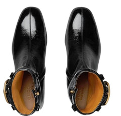 Black leather boots with gold accents on a light gray background