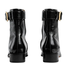 Black leather boots with gold buckles on a light gray background
