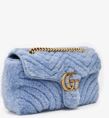 Blue textured handbag with gold chain and logo on a white background