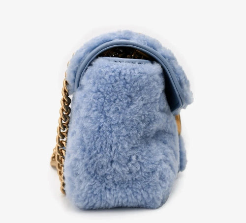 Blue fluffy handbag with a gold chain on a white background