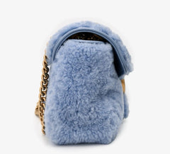 Blue fluffy handbag with a gold chain on a white background