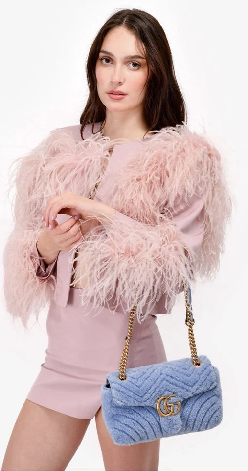 Woman holding a blue Gucci handbag against a white background