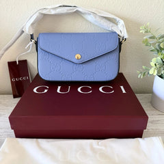 Blue Gucci handbag on a Gucci box with a plant in the background