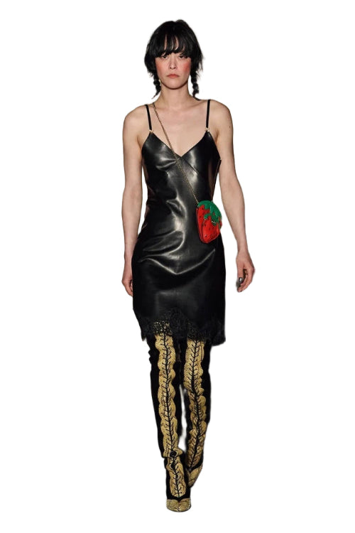 Model wearing a black slip dress with gold accents and a red rose detail on a stone staircase.