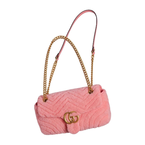 Pink quilted handbag with gold chain and logo on a light gray background