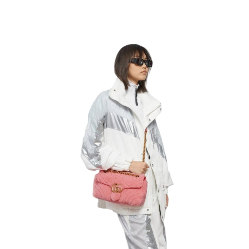 Person holding a pink quilted handbag against a plain background