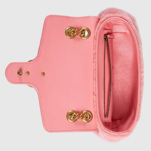 Pink handbag with gold hardware on a light gray background