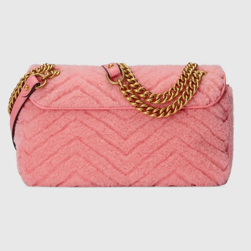 Pink quilted handbag with gold chain handle on a light gray background