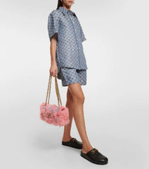 Person wearing a patterned outfit holding a pink fluffy bag on a white background