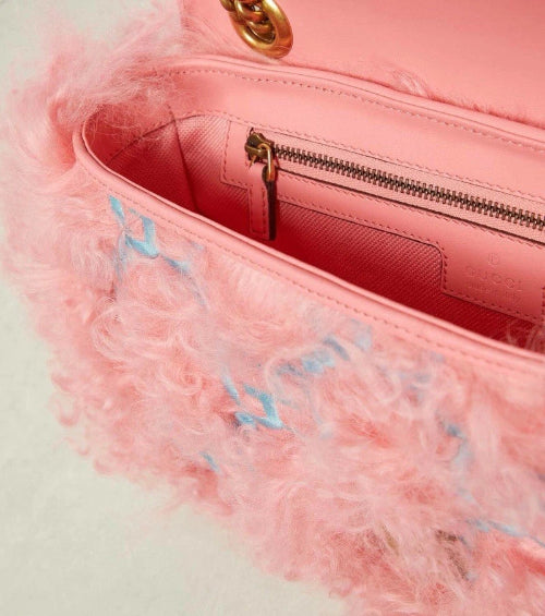 Pink handbag with fluffy texture and gold zipper on a light background