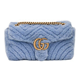 Blue textured handbag with gold chain and logo on a white background