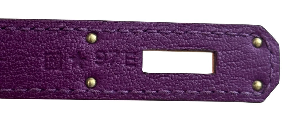 Close-up of a purple leather strap with gold studs and a brand logo.