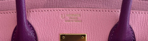 Close-up of a pink Hermès handbag with gold hardware.