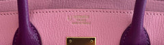 Close-up of a pink Hermès handbag with gold hardware.