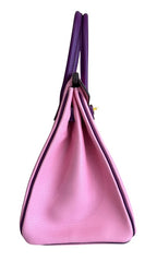 Pink handbag with purple handles on a white background