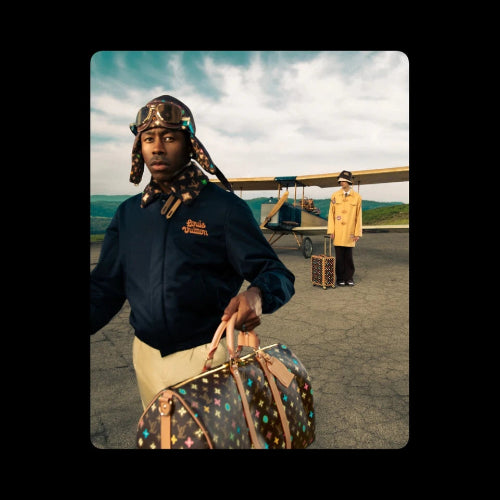 Man holding a colorful suitcase with another person in the background near an airplane on a tarmac.