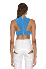 Person wearing a blue crop top with cut-out design and white pants on a white background